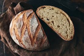 A loaf of no knead bread dusted in flour with artistic cuts in the crust.